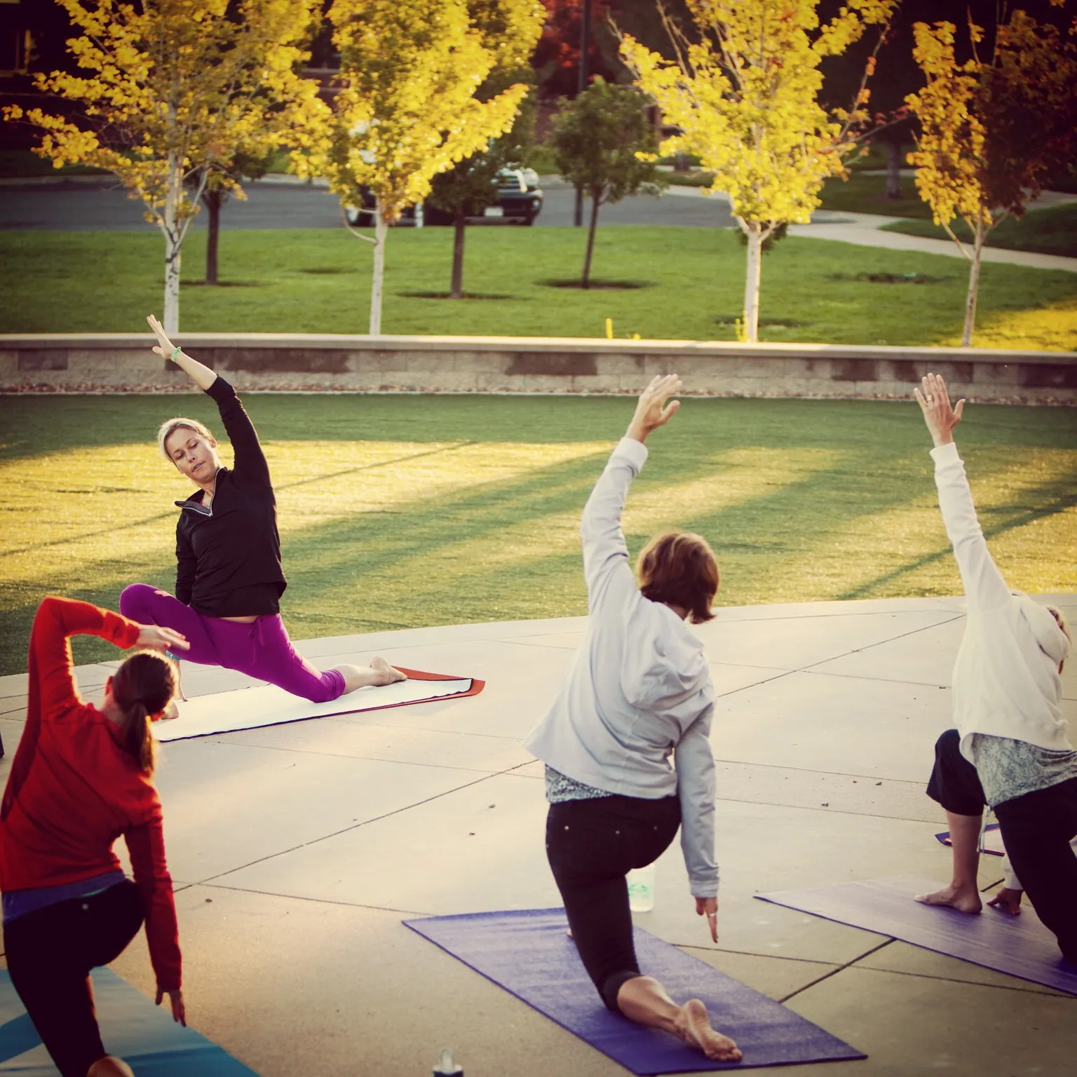 Outdoor yoga class on a paved circle in a park with fall trees
