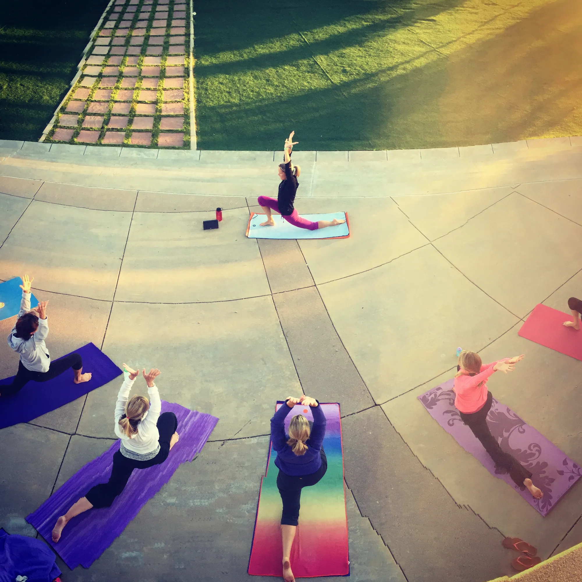 Aerial view of a yoga class on colorful mats on a curved concrete plaza