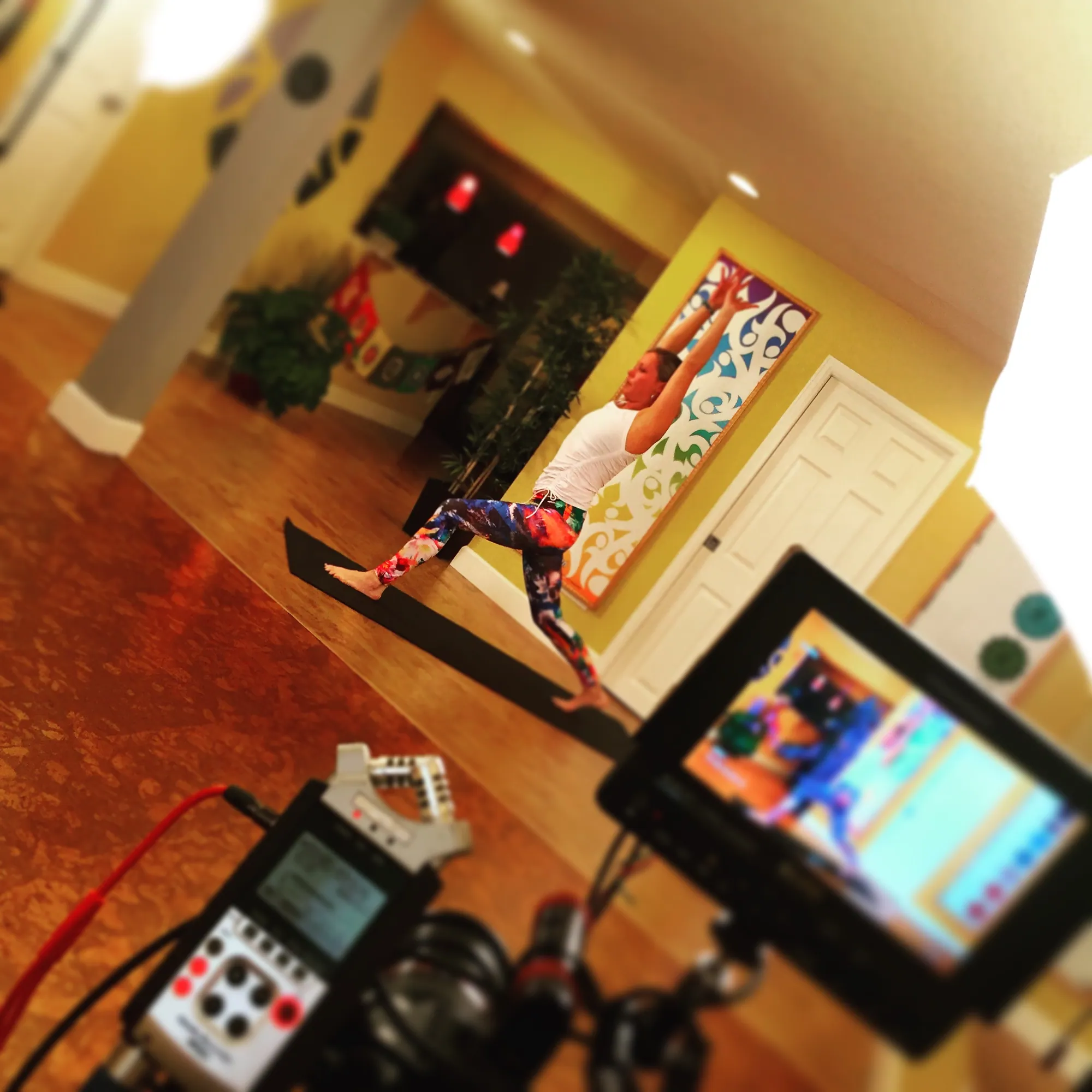 Camera, monitor and audio recorder filming a yoga teacher in a studio