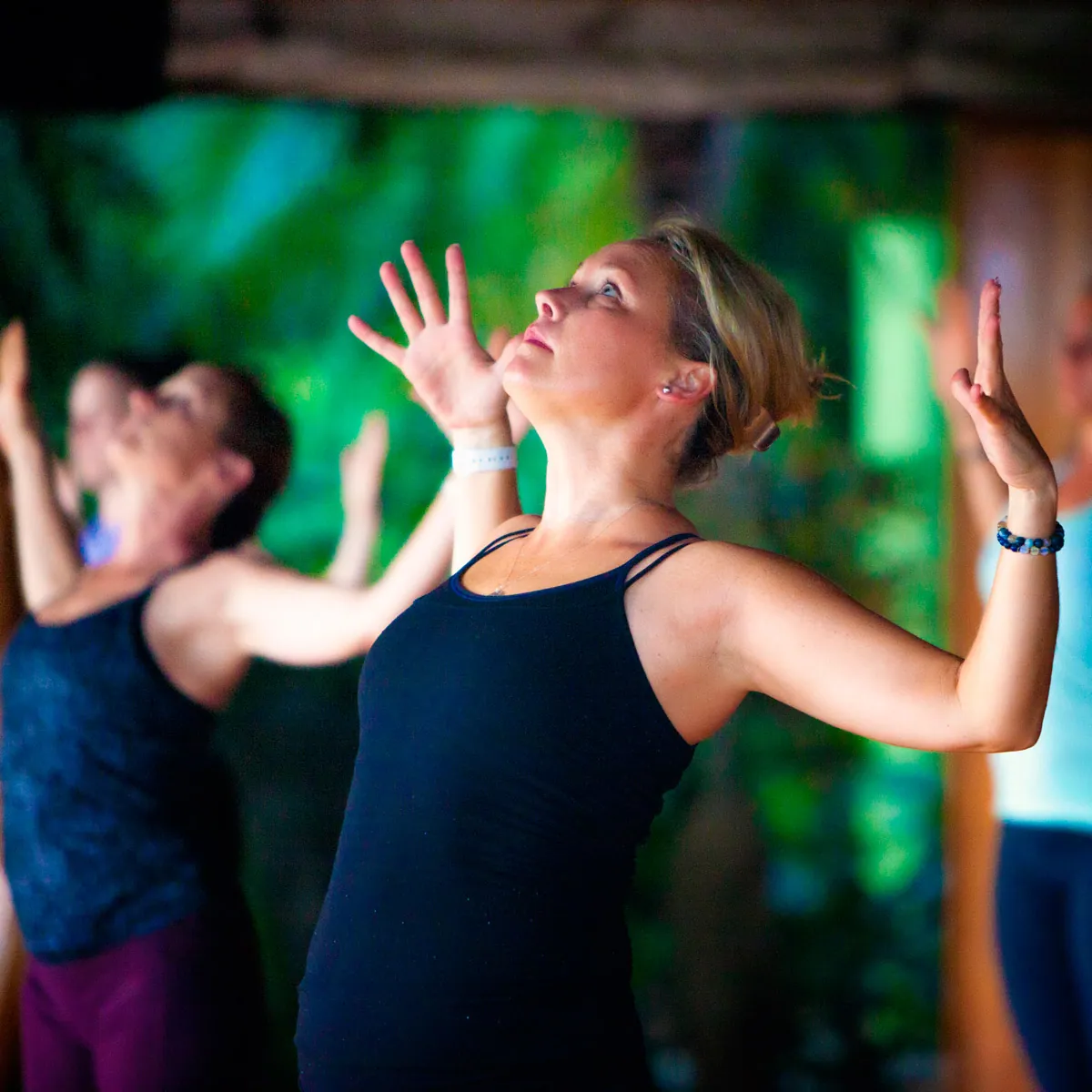 Woman in a standing yoga pose with hands raised and head tilted back