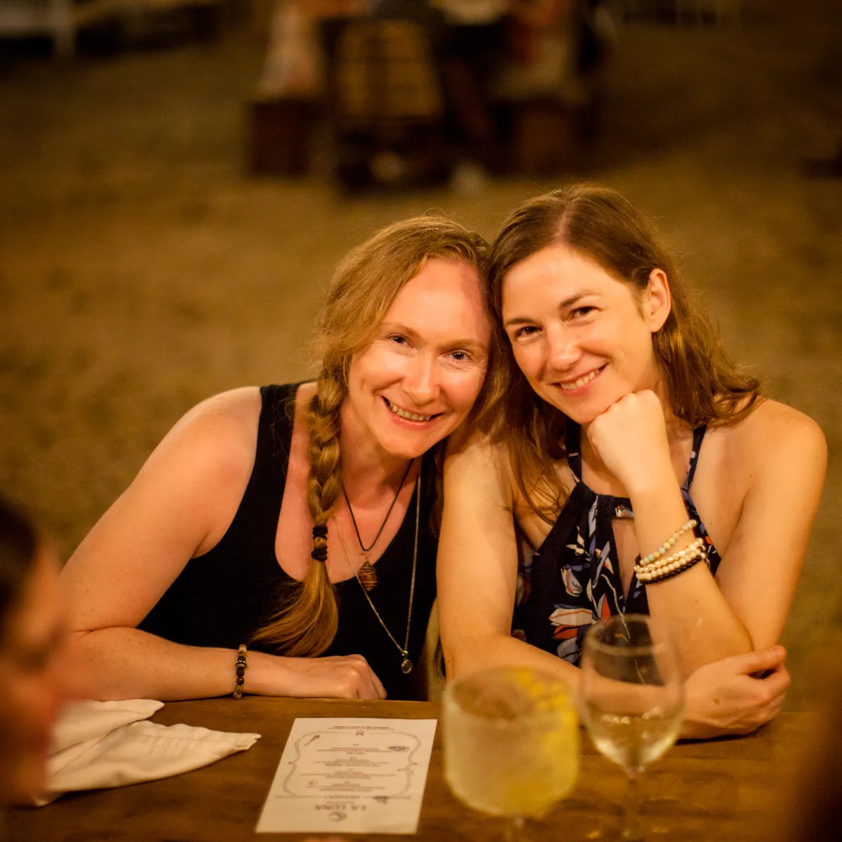 Two smiling women sitting close at a dinner table