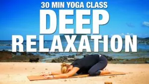Class thumbnail: 30 Min Deep Relaxation, woman in child's pose on a beach
