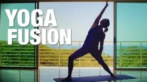 Class thumbnail: Yoga Fusion, silhouetted woman in a standing pose before ocean-view windows