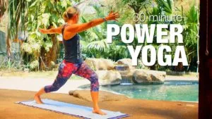 Class thumbnail: 30 minute Power Yoga, woman in a warrior pose with arms out by a pool