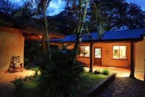 Casa Colorado guest house lit at dusk behind palm trees