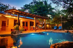 Casa Colorado covered terrace and pool glowing at dusk among trees