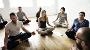 Group of adults meditating seated on the floor in a bright room