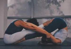 Two people in a seated partner yoga forward fold