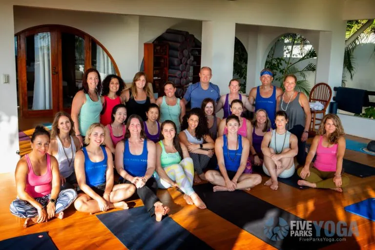 Group of retreat guests smiling together on yoga mats in a villa
