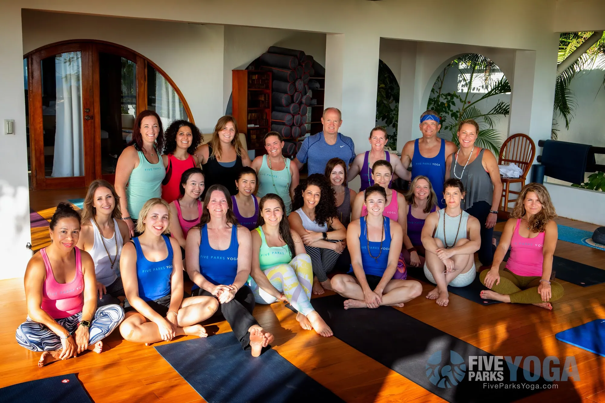 Group of retreat guests smiling together on yoga mats in a villa