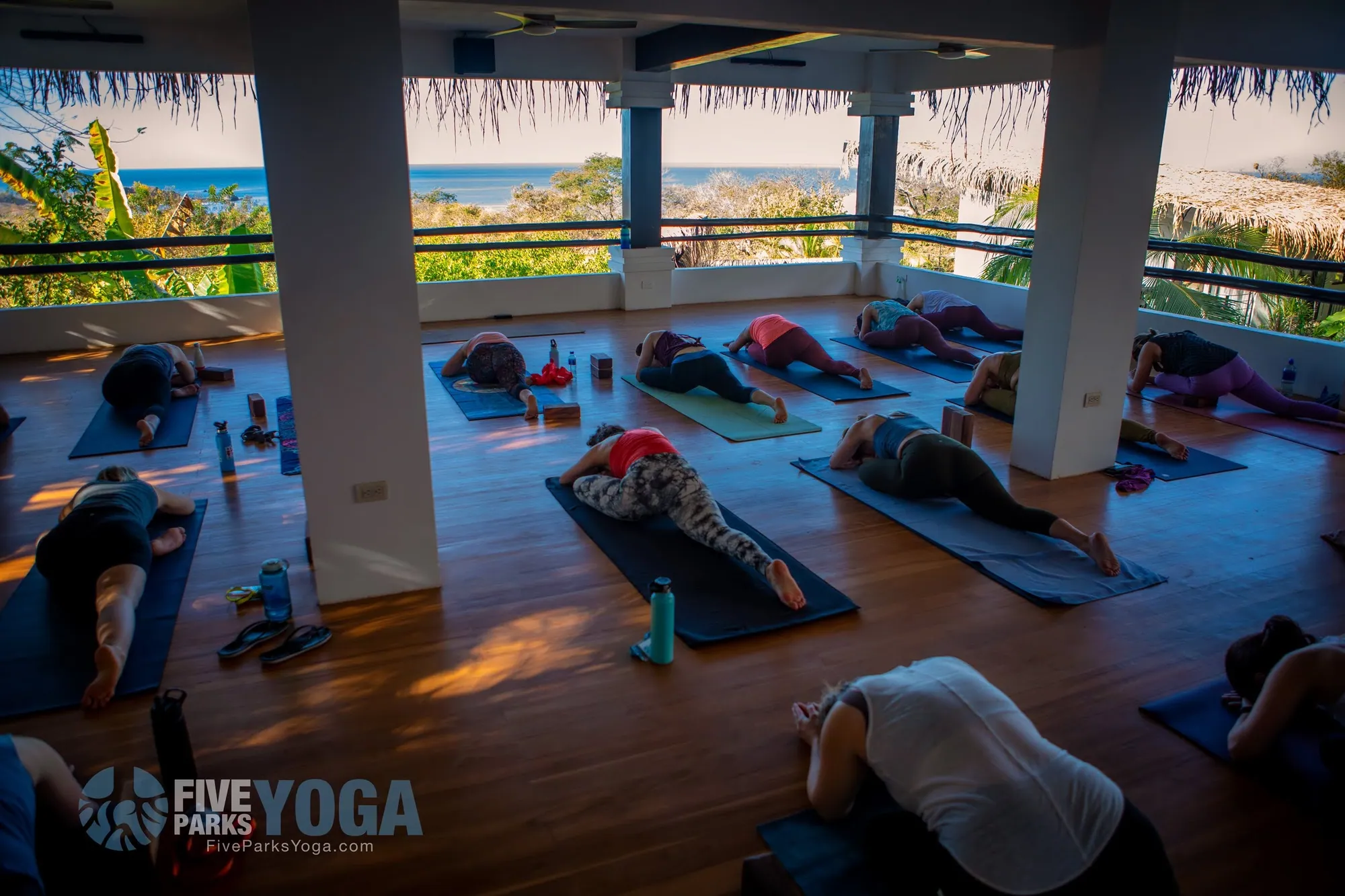 Retreat guests in yoga poses in an open-air studio overlooking the ocean