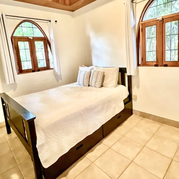 Karma Jungle View penthouse bedroom with a queen bed and arched windows at Casas Kismet, Nosara