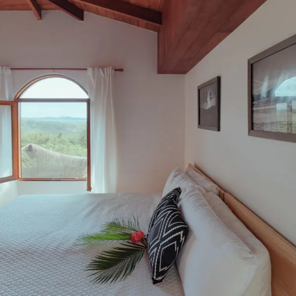 Karma Penthouse king suite with an arched window looking out over the jungle at Casas Kismet, Nosara