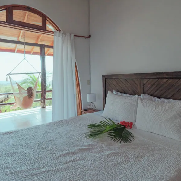 Karma queen suite with a guest relaxing in a hammock chair on the ocean view balcony, Casas Kismet