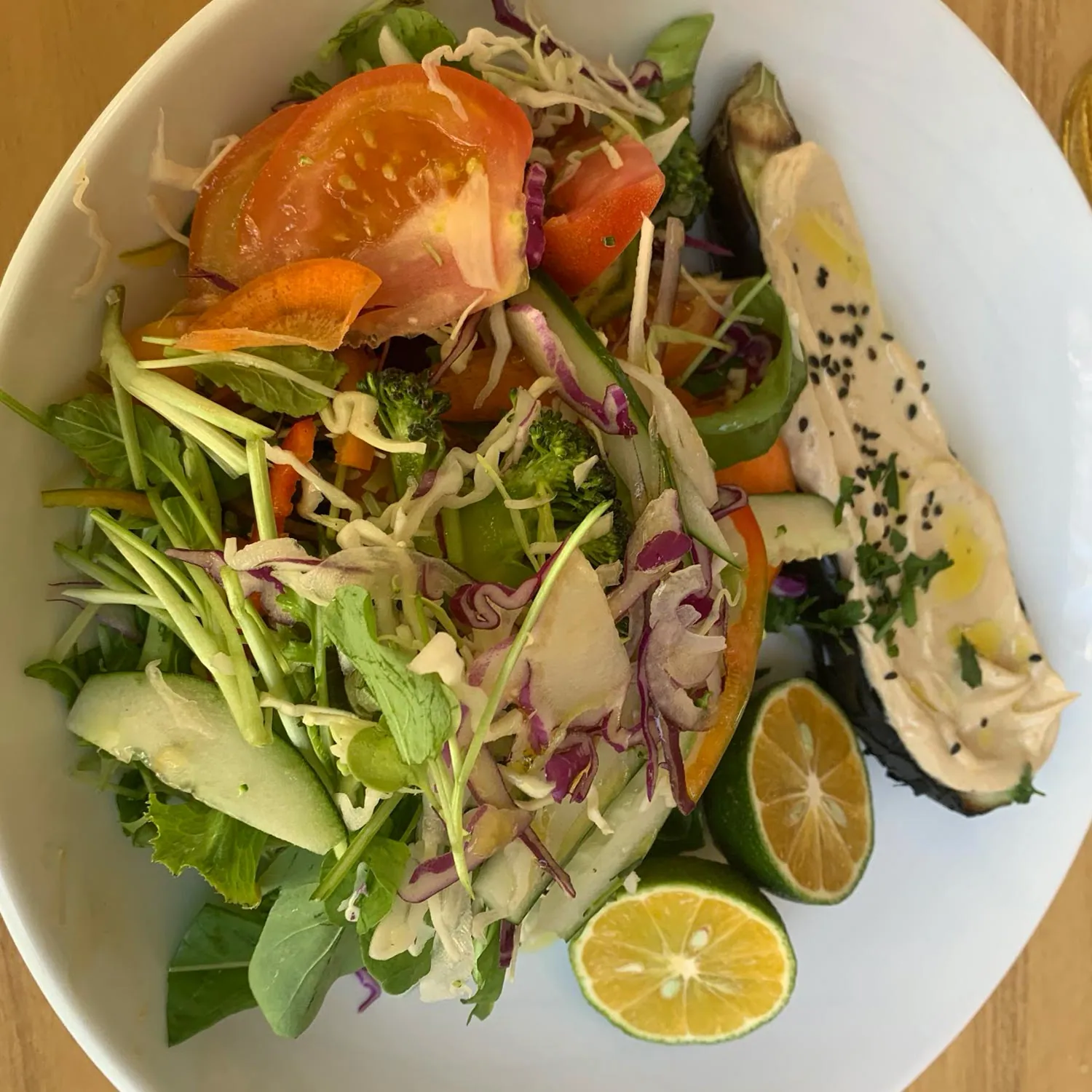 Salad with hummus, avocado and a lime wedge
