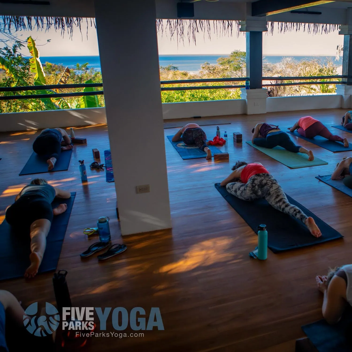 Guests resting on yoga mats in an open studio with an ocean view