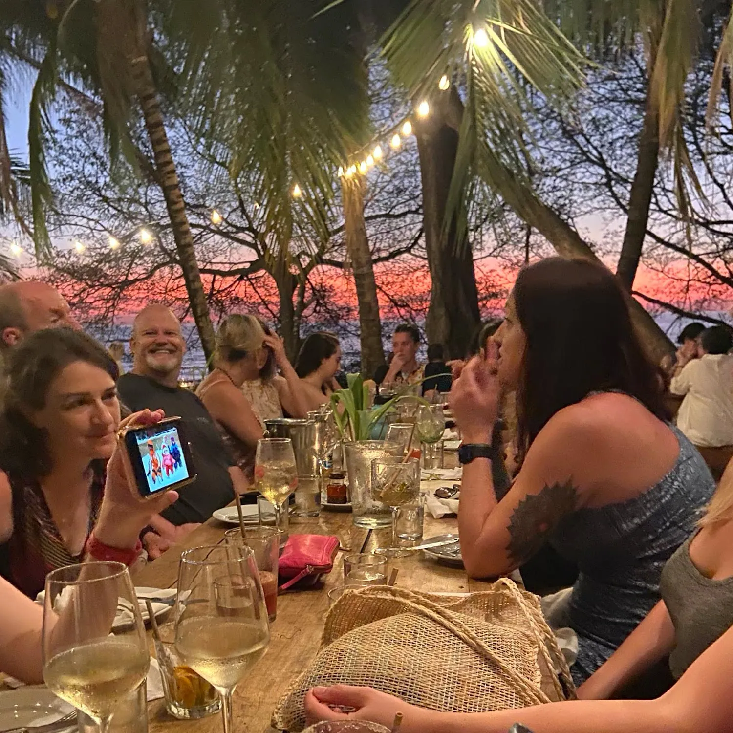 Retreat guests gathered at a dinner table at sunset under string lights