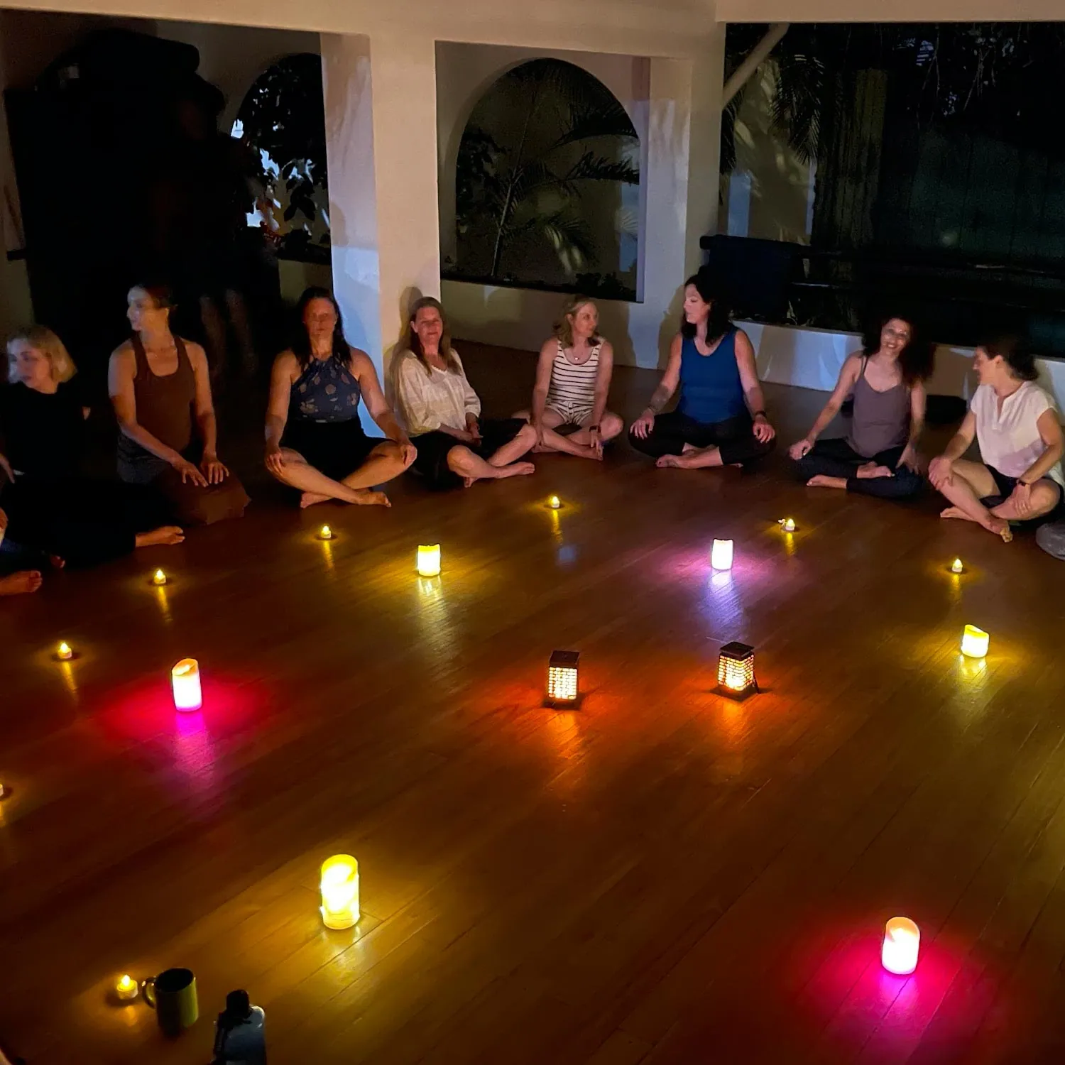 Guests seated in a circle with candles on a studio floor