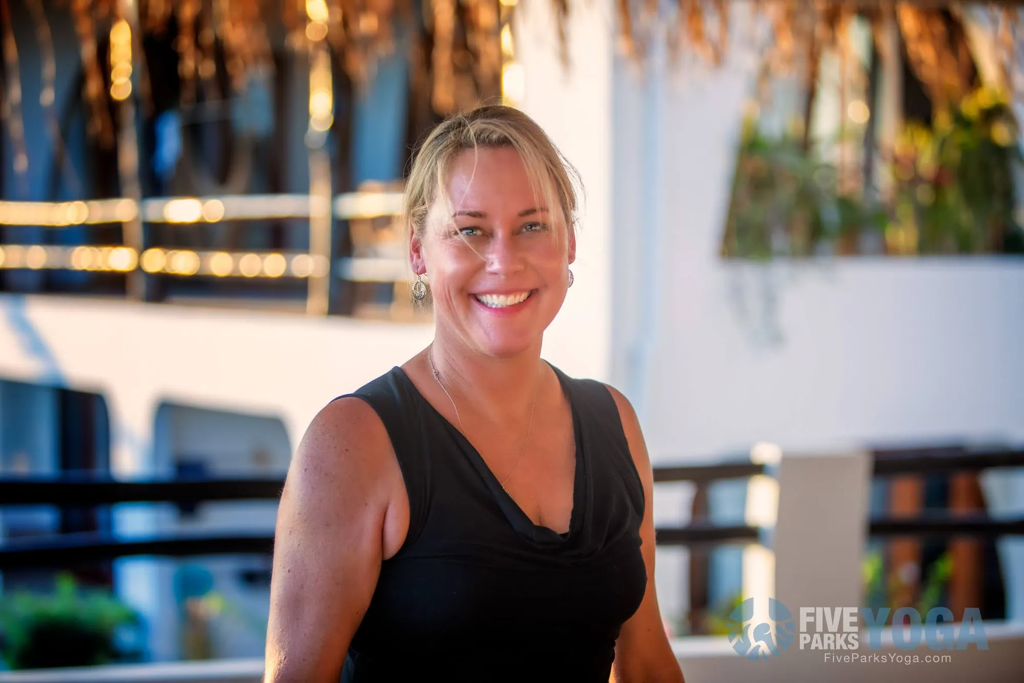 Smiling woman in a black tank top on a balcony