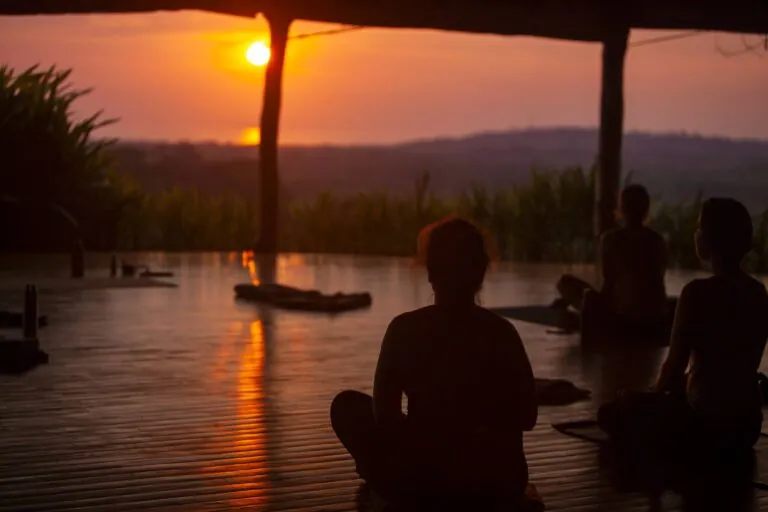 Silhouettes of people at a yoga session at sunset