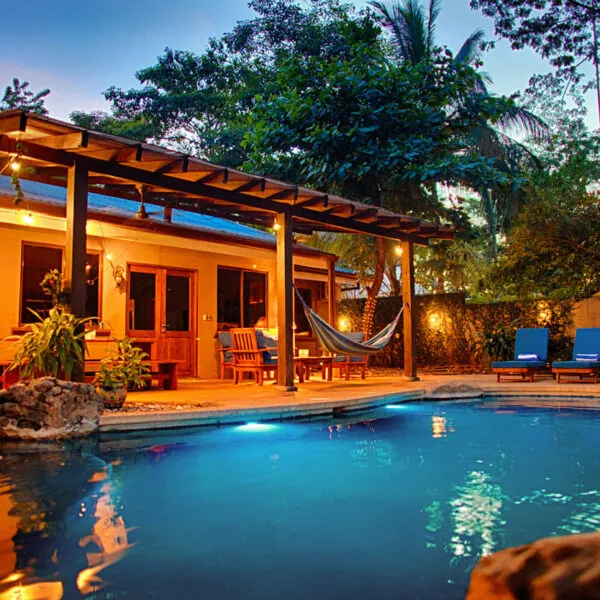 Lit pool and covered patio with a hammock at dusk at Casa Colorado, Tamarindo, Costa Rica