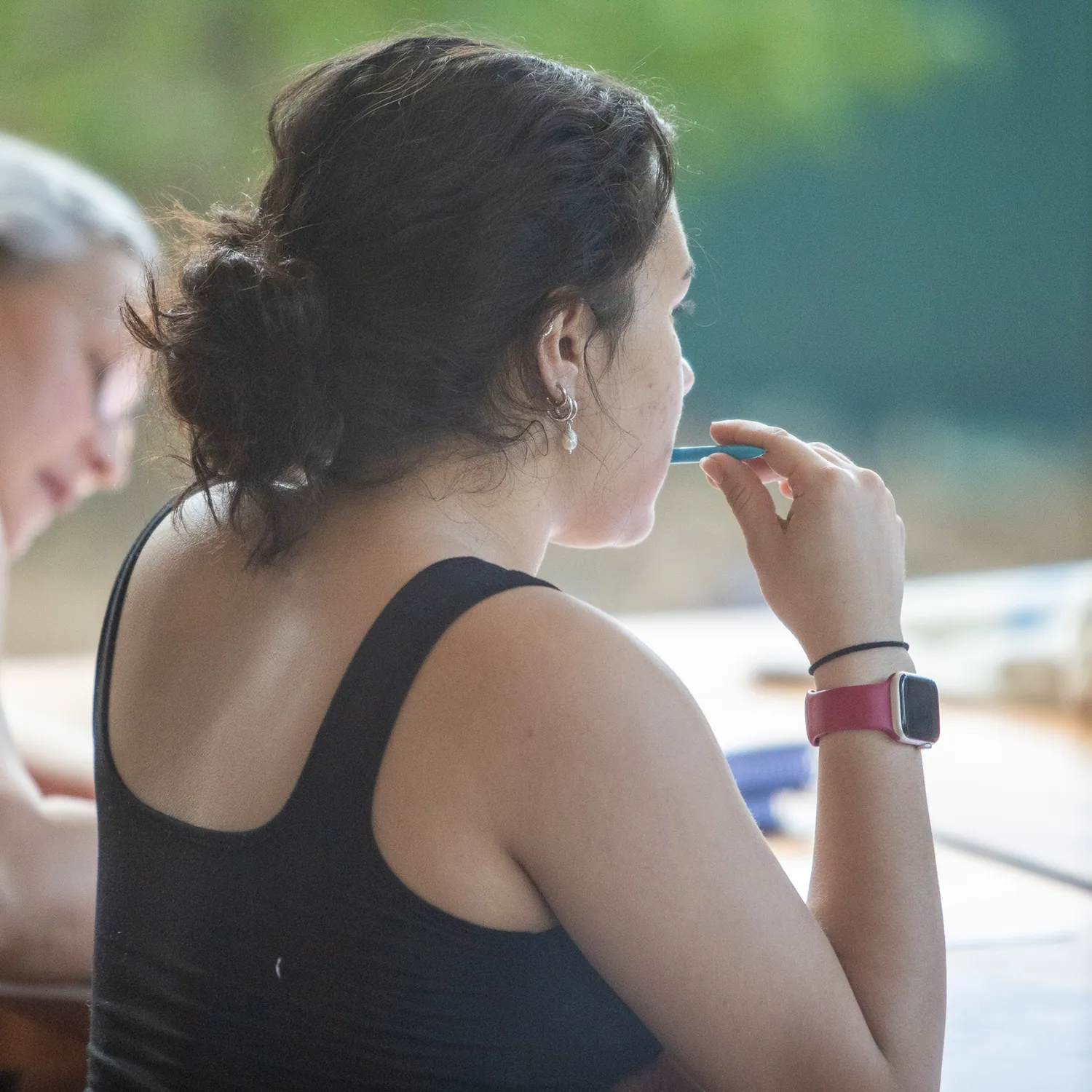 Teacher training student in profile holding a pen to her lips