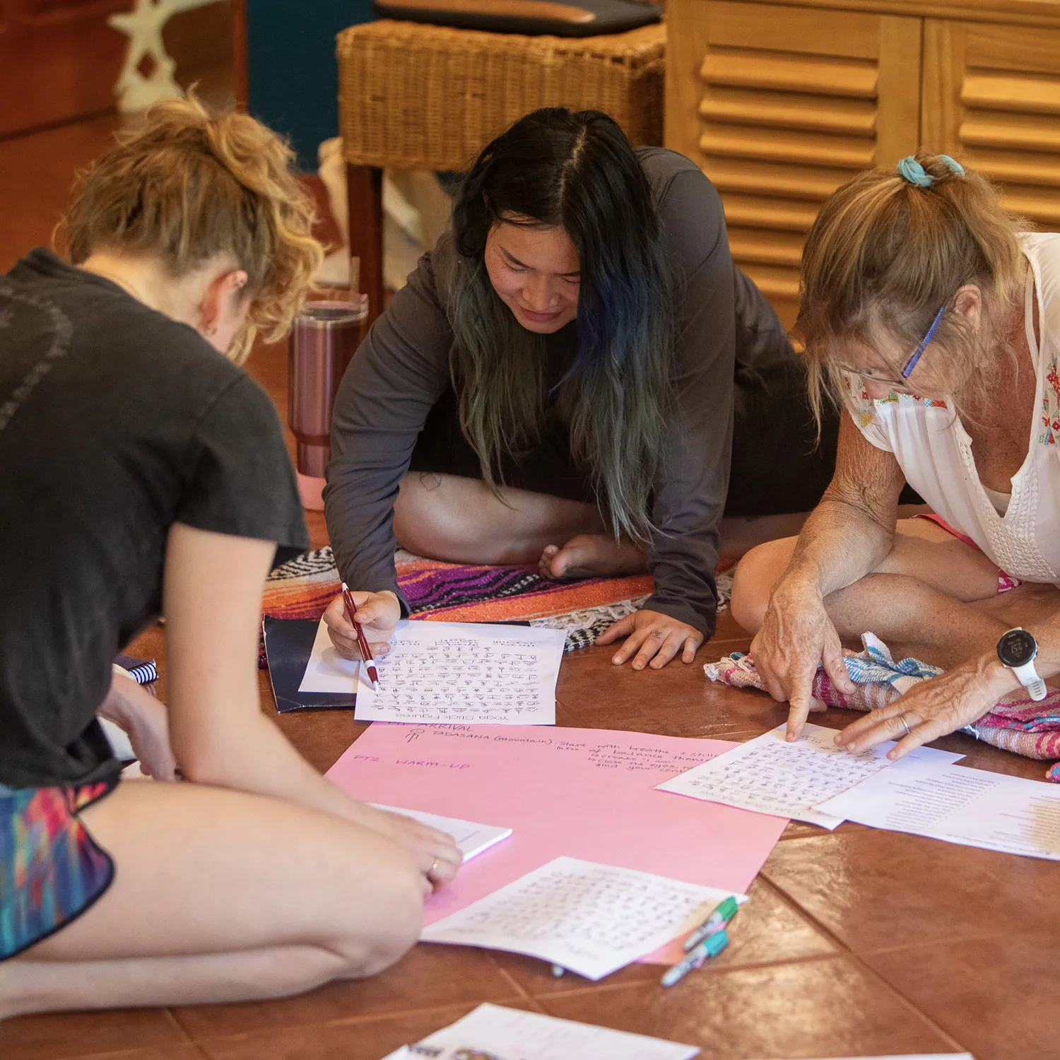 Teacher training students writing together on pink paper on the floor