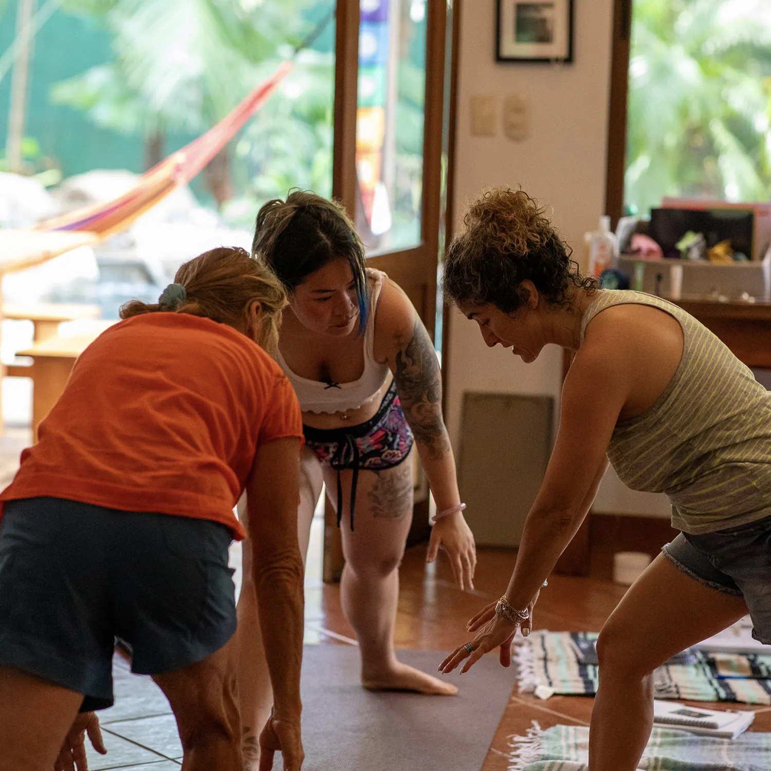 Three teacher training students bending over materials on the floor