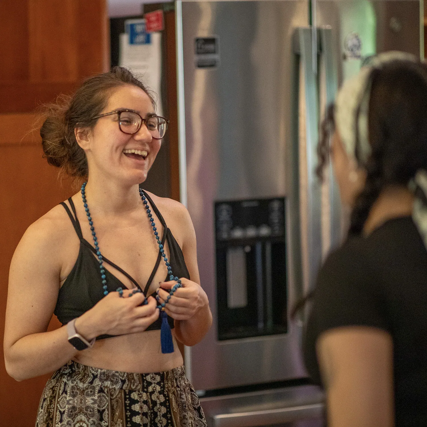 Smiling teacher training student wearing glasses and a mala necklace