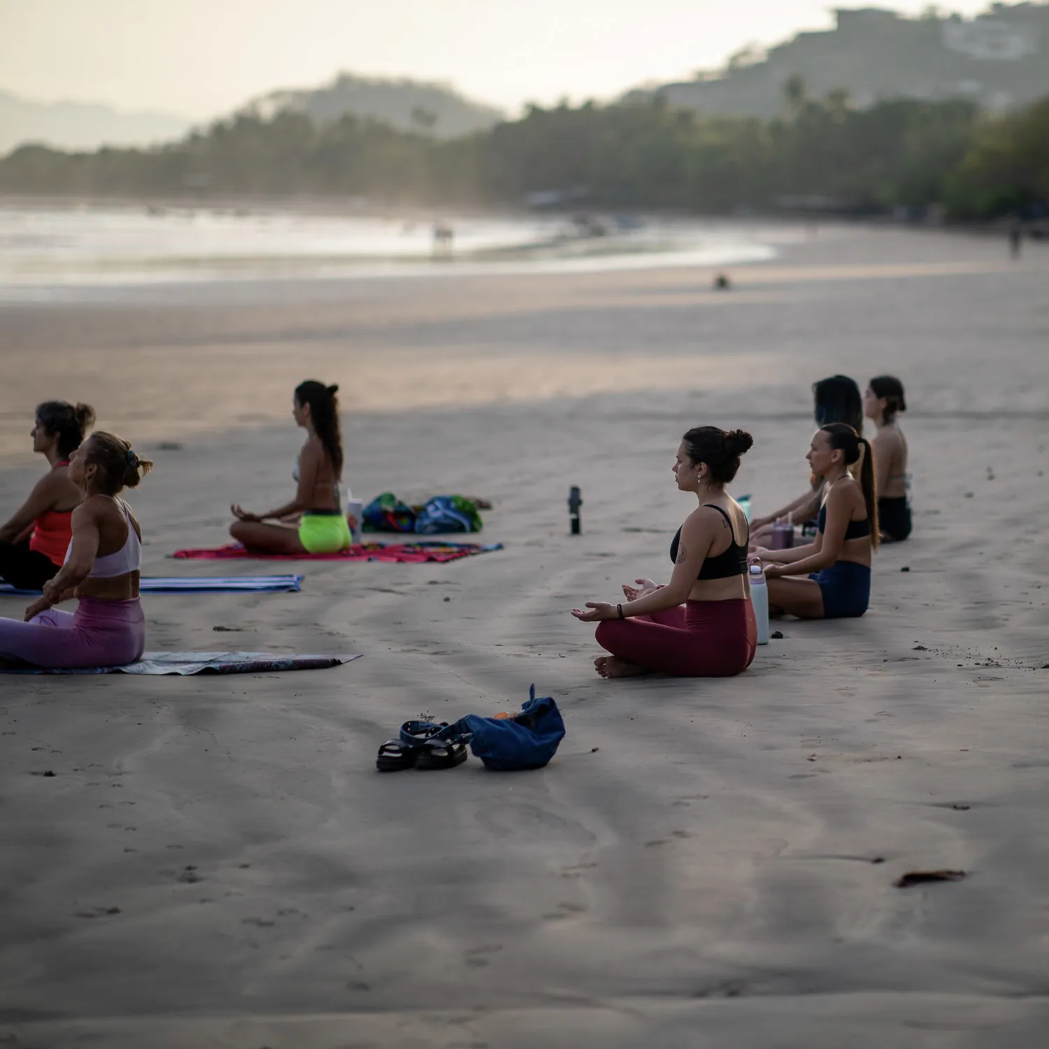 Teacher training students meditating on the beach at dusk in Tamarindo, Costa Rica