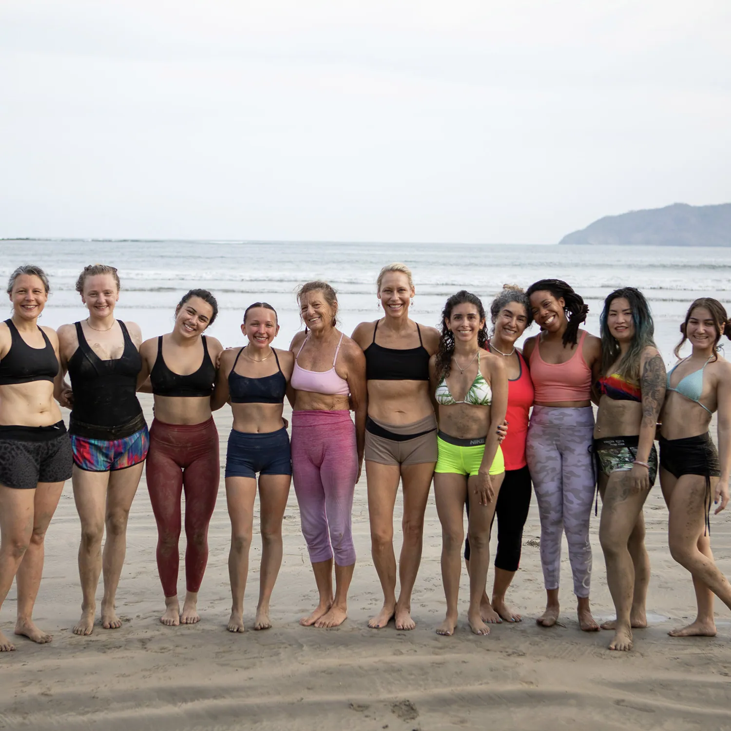 Yoga teacher training group standing arm in arm on the beach in Tamarindo, Costa Rica