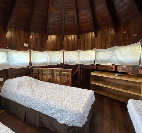 Bungalow loft with twin beds under a round wood ceiling, Tamarindo teacher training lodging