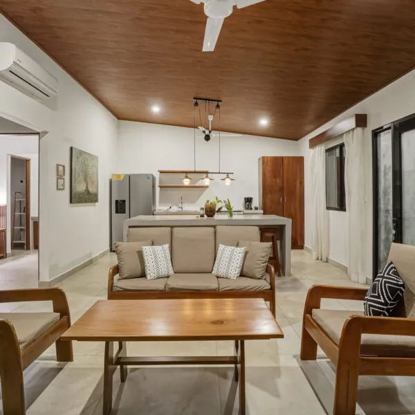 Pool House living room with sofa, armchairs and open kitchen at Casas Kismet, Nosara