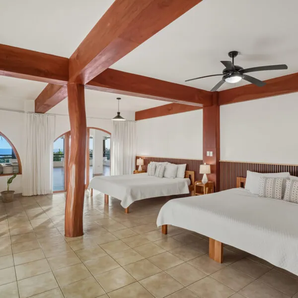 Dharma Quad shared room with wood beams and several beds at Casas Kismet, Nosara