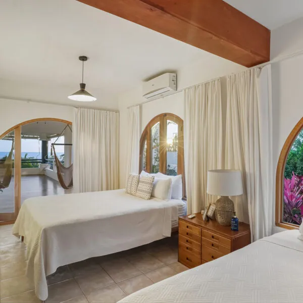 Dharma Queen shared room with two beds and arched doors to a hammock balcony at Casas Kismet, Nosara